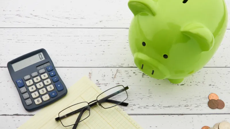 Calculator, coins and a piggy bank on a desk